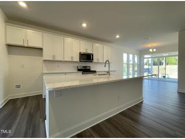 Modern kitchen featuring white cabinets, stainless steel appliances, and a large island with granite countertops at 500 Traditions Grande Blvd # 22, Wake Forest, NC 27587