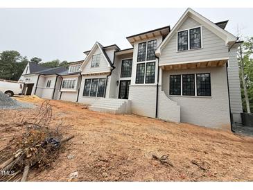 Newly constructed home features a gray painted brick exterior, black framed windows, and modern architectural design at 7013 Buckhead Dr, Raleigh, NC 27615