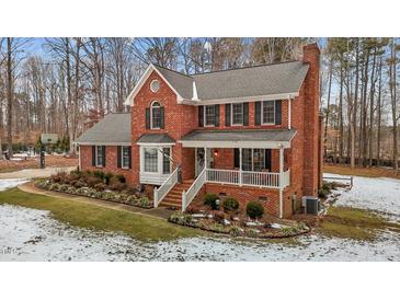 Brick two-story house with a white porch, landscaping, and snowy yard at 4139 Somerset Dr, Oxford, NC 27565