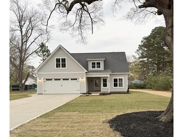 Charming home featuring a gray exterior, well-manicured lawn, and a two-car garage at 504 Tucker St, Four Oaks, NC 27524
