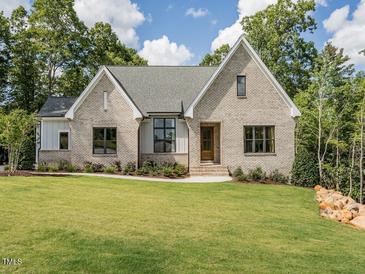 Brick home with a pitched roof, large windows, and a landscaped lawn at 64 W Beech Slope Ct, Chapel Hill, NC 27517