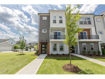 Modern townhome showcasing clean lines, mixed siding, a small balcony, and professionally landscaped front yard at 2117 Treelight Way, Wendell, NC 27591