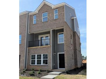New construction townhouse with brick and siding, balcony, and manicured landscaping at 201 Broomgrove Way, Wake Forest, NC 27587