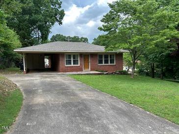 Cozy single-story brick home featuring an attached carport and a well-maintained front yard with mature trees at 404 W Ninth St, Siler City, NC 27344