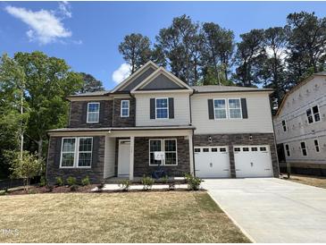 Two-story home featuring a stone and siding exterior with a two-car garage and manicured front lawn at 752 Portland Rose Dr, Knightdale, NC 27545