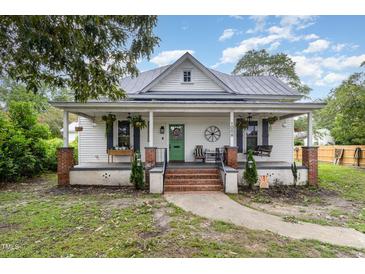 Charming white farmhouse with a front porch and brick steps at 1006 W Broad St, Dunn, NC 28334
