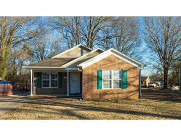 Brick ranch home with green shutters and a landscaped lawn at 411 Wade St, Graham, NC 27253