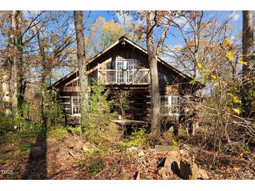 Rustic log cabin nestled in woods, features balcony and large windows at 90 Little Indian Creek Rd, Goldston, NC 27252