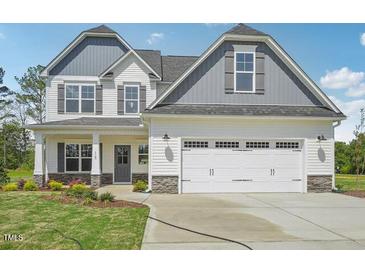 Charming two-story home with a white exterior, gray accents and a two-car garage at 18 Hewitt Woods Dr, Clayton, NC 27527