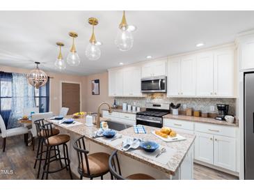 Bright kitchen with granite countertops, an island with seating, and modern appliances at 402 W Clay St, Mebane, NC 27302