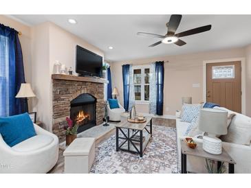Cozy living room with a stone fireplace, ceiling fan, and lots of natural light at 402 W Clay St, Mebane, NC 27302
