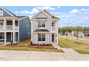 Charming gray two-story home featuring a front porch and well-manicured landscaping at 704 Georgia'S Landing Pkwy # 15, Raleigh, NC 27603