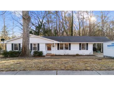 White ranch house with a spacious yard and mature trees at 1303 Claymore Dr, Garner, NC 27529