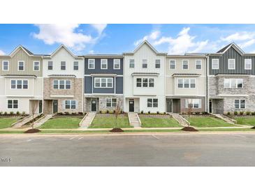 Modern townhomes feature varied siding and stonework, complemented by well-manicured lawns and inviting front entrances at 707 Lucky Clover Way, Fuquay Varina, NC 27526