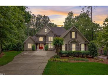 Stately stone home with manicured landscaping, a red front door, and abundant natural light at 1300 Caistor Ln, Raleigh, NC 27614