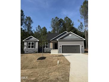 Charming single-story home with gray siding, stone accents, an attached garage, and a well-manicured lawn at 65 Watermelon Dr, Franklinton, NC 27525