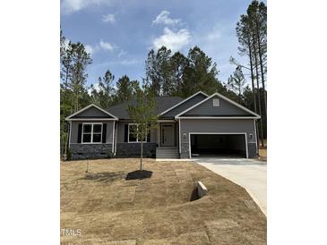 Attractive single-story home with gray siding, stone accents, and an attached two-car garage on a sunny lot at 65 Watermelon Dr, Franklinton, NC 27525