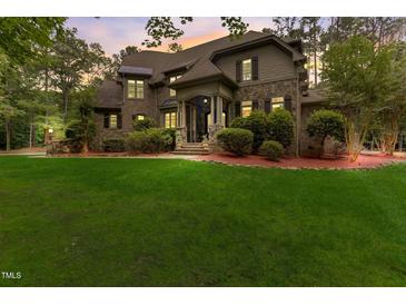 Brick house with stone accents, a large yard, and a three-car garage at 6729 Greywalls Ln, Raleigh, NC 27614