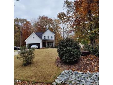 Charming two-story home with white siding, black roof and trim, and a well-manicured lawn in a serene setting at 716 Spirit Hill Dr, Hillsborough, NC 27278