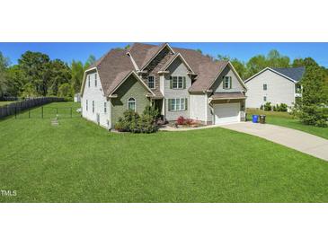 Traditional two-story home with a lush green lawn, attached garage and stone chimney feature at 7945 Parker Mill Trail, Fuquay Varina, NC 27526