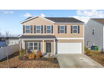 Two-story house with tan siding, white garage door, and landscaping at 105 Kcf Dr, Elon, NC 27244