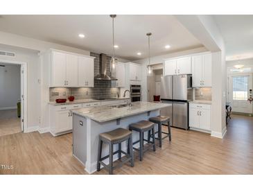 Modern kitchen features stainless steel appliances and an island with barstool seating at 105 Scoville Rd, Garner, NC 27529