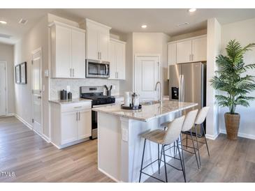 Modern kitchen featuring white cabinets, stainless steel appliances, granite counters, and an island with seating at 1060 Winding Spring Dr, Mebane, NC 27302