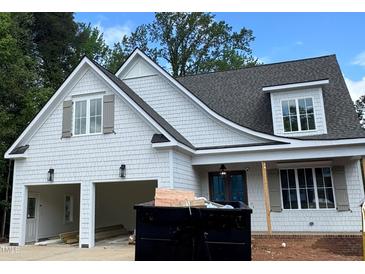 An exterior view of a home with white siding, grey trim, and a garage, and construction debris at 129 Windel Dr, Raleigh, NC 27609