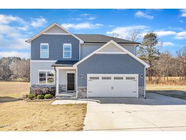 Two-story house with blue siding, stone accents, and a two-car garage at 148 Aylebury Rdg, Zebulon, NC 27597