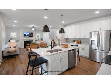 Open concept kitchen features white cabinets, stainless steel appliances, and a large island at 86 Macy Cir, Wendell, NC 27591