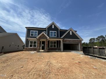 New construction home featuring stone accents, an attached garage, and a classic two-story design under a blue sky at 1104 Opal Ln # 104, Durham, NC 27705