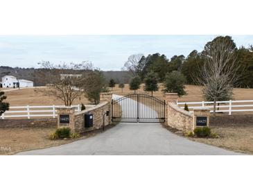 Brick pillars and wrought iron gates open to a long driveway leading to a beautiful home at 14425 Nc-96 N Hwy, Zebulon, NC 27597