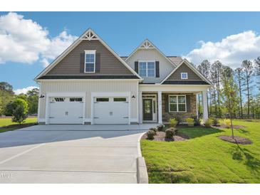 Charming two-story home boasts a manicured lawn, a two car garage, and welcoming stone accents on the porch at 35 Hewitt Wds Dr, Clayton, NC 27527