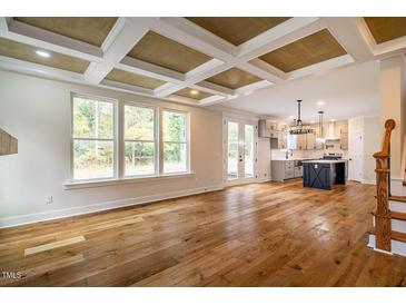 Open living room with hardwood floors, coffered ceiling, and fireplace at 4860 Fayetteville Rd, Durham, NC 27713
