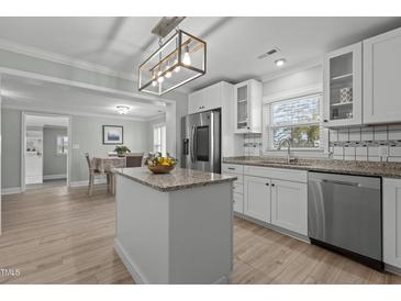 Well-lit kitchen features an island, stainless steel appliances, white cabinets, granite countertops, and an adjacent dining area at 5088 Christian Light Rd, Fuquay Varina, NC 27526