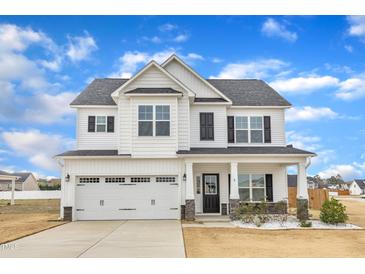 Charming two-story home with white siding, black shutters, covered porch, and a two car garage at 8 Looping Horse Cir, Angier, NC 27501