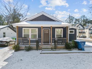 Charming craftsman style home with a covered porch and snowy front yard at 819 Cumberland St, Raleigh, NC 27610