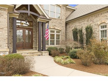 Inviting brick home featuring an arched entryway and decorative wood and iron front doors at 101 Bonica Creek Dr, Garner, NC 27529
