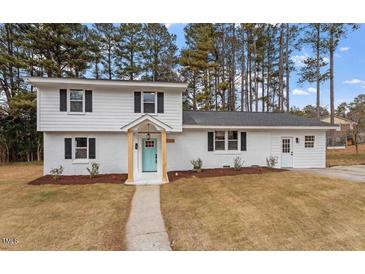 Charming white two-story home featuring a manicured lawn, fresh landscaping, and an eye-catching light-blue front door at 3305 Victor Pl, Raleigh, NC 27604