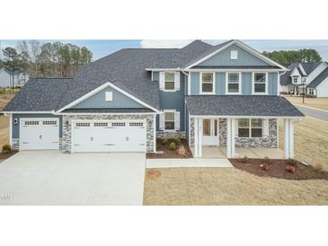 Beautiful blue two-story home featuring a three-car garage and stone veneer accents at 514 Glenkirk Pl, Garner, NC 27529