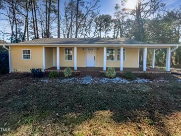 Cute yellow house with a front porch, and nicely landscaped yard at 6307 Tryon Rd, Cary, NC 27518