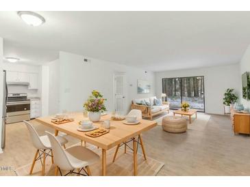 Bright and airy living and dining area with wood floors, modern furnishings, and sliding glass door to the outside at 642 Pine Ridge Pl, Raleigh, NC 27609