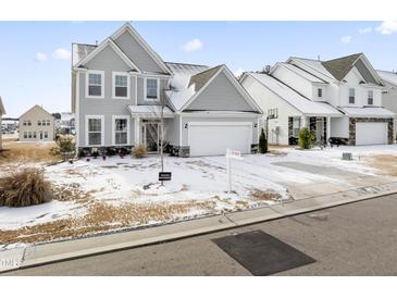 Two-story house with gray siding, a white garage door, and a snow-covered lawn at 803 Golden Plum Ln, Zebulon, NC 27597