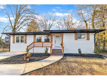 Charming ranch home with white exterior, wood accents, and landscaped yard at 919 Fiske St, Durham, NC 27703