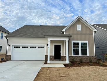 Two-toned Craftsman style home with a white garage door and landscaping at 964 Channel Drop Lp, Zebulon, NC 27597