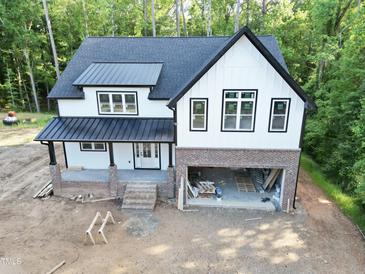 Stunning two-story home showcasing a white exterior with black accents and a brick-lined garage at 301 W College St, Louisburg, NC 27549