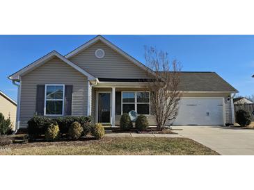 Tan house with a white garage door and landscaping at 670 Meadowtop Cir, Burlington, NC 27217