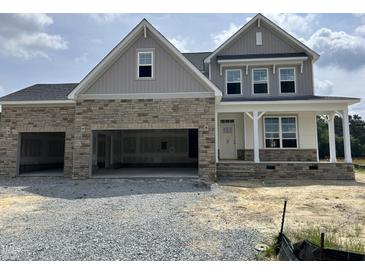 Charming two-story home featuring stone accents, a welcoming porch, and a convenient two-car garage at 71 Priming Way, Angier, NC 27501