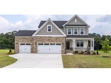 Charming two-story home features a stone facade, inviting front porch, three-car garage, and well-manicured lawn at 71 Priming Way, Angier, NC 27501