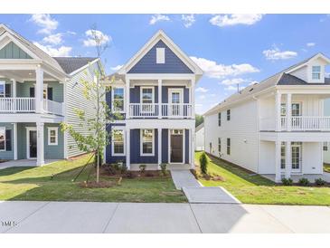 Charming blue two-story home with a front porch and manicured lawn under a clear sky at 720 Georgias Landing Pkwy # 11, Raleigh, NC 27603